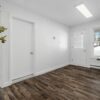 a white room with wood floors and a vase with flowers